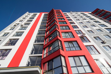 View at sky between apartment buildings. City landscape. Blue sky with clouds. Sunny day.