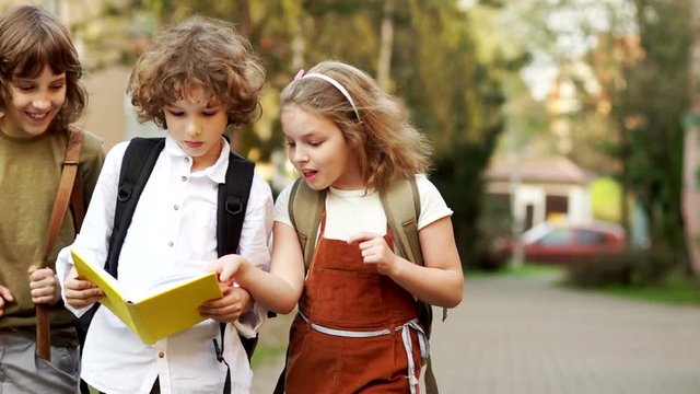 Three schoolchildren are enthusiastically discussing the book on the way from school. Back to school. Effective methods of teaching