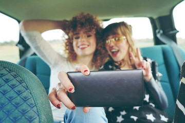 Dos chicas viajando juntas y haciéndose fotos con su teléfono móvil 