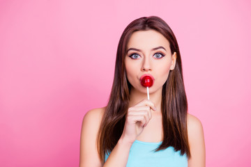 Close up portrait of beautiful cheerful deligthful lovely cute charming wonderful girl kissing red lollipop on stick isolated on pink background, copy space