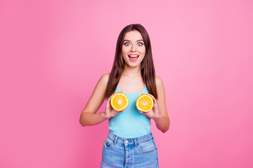 Portrait of charming pretty playful fancy funky comic humorous excited cheerful wearing casual blue jeans denim outfit with open mouth girl showing oranges on breast, isolated on pink background © deagreez
