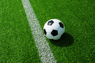 Fototapeta na wymiar Fussball Ball neben der Markierung Linie auf grünem Kunstrasen am Feld