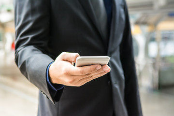 Business man is using smartphone that he holding in the right hand