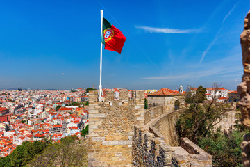 Beautiful large waving portuguese flag over the tower of Saint Jorge Castle against the blue sky, Lisbon, Portugal