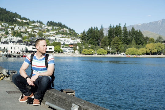 Hombre joven sentado al atardecer en un puerto