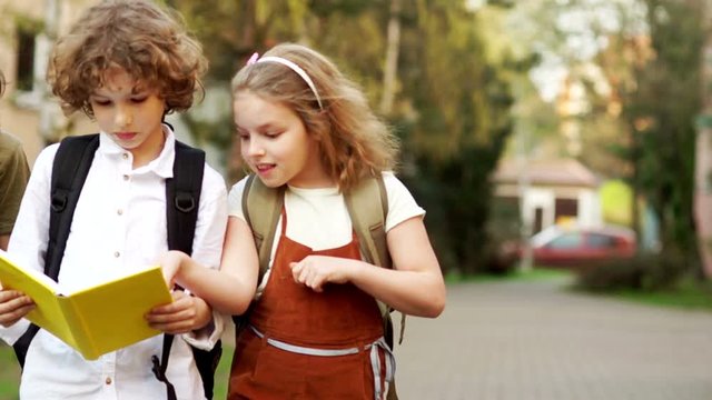 Two Boys And A Girl. Three Schoolchildren Are Enthusiastically Discussing The Book On The Way From School. Back To School. Effective Methods Of Teaching. Children's Day. Day Of Knowledge