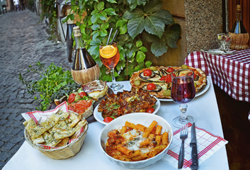 A summer  dinner .Unidentified people eating traditional italian food in outdoor restaurant in Trastevere district in Rome, Italy.   .Tasty and authentic Italian kitchen