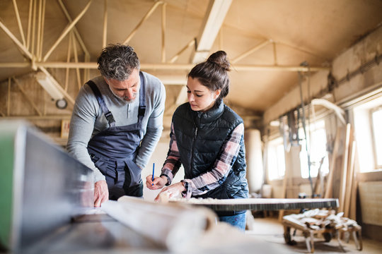 Man And Woman Workers Working In The Carpentry Workshop.