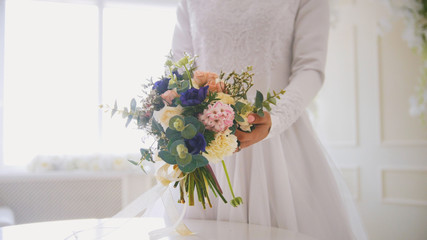 Hands of muslim bride in white dress holding the bouquet of flowers