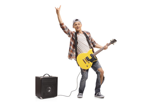 Teenager with an electric guitar and an amplifier making a rock gesture