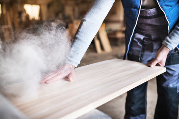 A man worker in the carpentry workshop, working with wood.