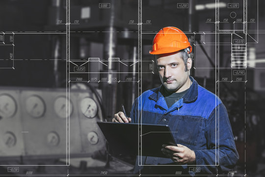 Working in the factory with a tablet in hand against the background of the equipment in front of the screen with an engineering drawing