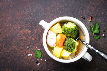 Chicken and vegetables soup on dark table. 