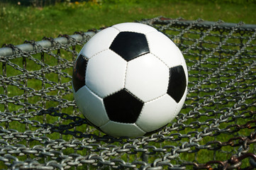 Fototapeta na wymiar Fussball klassisch auf einem Tor mit Gitter im Sommer