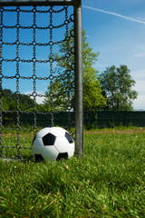 klassischer Fussball schwarz weiss bei einem Tor neben dem Pfosten mit Gitter im Sommer © Stefano Pepperino