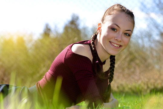 Smiling caucasian teenager girl liyng in grass on garden.