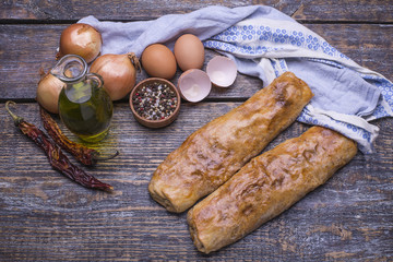 Homemade baking - strudels with meat and cabbage on a wooden board, background