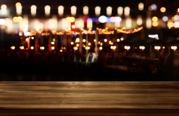 Image of wooden table in front of abstract blurred restaurant lights background.