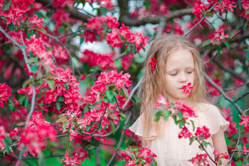 Naklejka premium Adorable little girl enjoying spring day in apple blooming garden