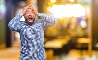 African american man with beard stressful keeping hands on head, terrified in panic, shouting at night