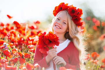 Cute smiling blonde child girl is wearing wreath from red flowers in poppy field