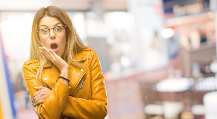 Beautiful young woman happy and surprised cheering expressing wow gesture at restaurant