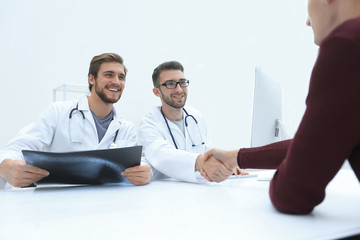 Obraz premium Smiling doctor at the clinic giving an handshake to his patient