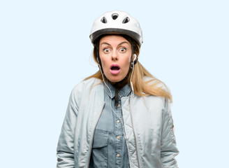 Young woman with bike helmet and earphones scared in shock, expressing panic and fear