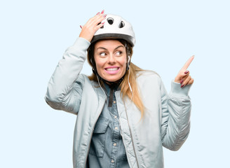 Young woman with bike helmet and earphones pointing away side with finger