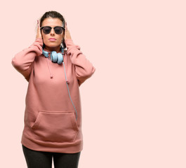 Young sport woman with headphones and sunglasses thinking and looking up expressing doubt and wonder