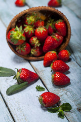 Fresh juicy strawberries with leaves on blue wooden background.