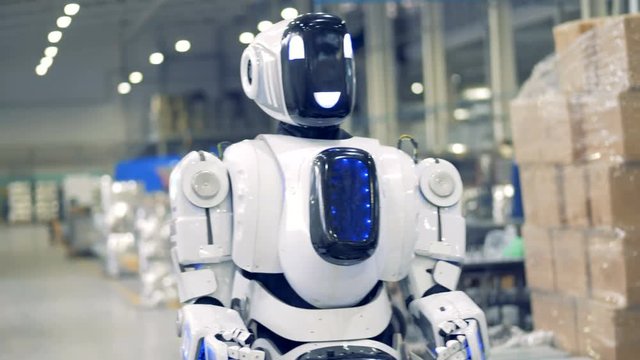 Smiling robot is walking forwards in factory premises