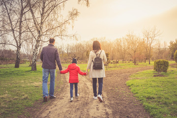 Happy young family spending time together outside in nature. parents holds the hands of a small children