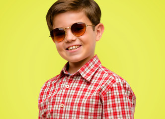 Fototapeta premium Handsome toddler child with green eyes confident and happy with a big crazy smile laughing over yellow background