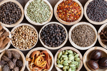 Group of indian spices in coconut bowls on wooden background