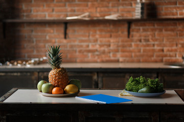 Fruit and vegetable detox diet food concept. Fresh apple, lemon, pineapple, avocado on the wooden table in the kitchen with loft brick wall background