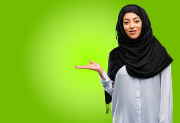 Young arab woman wearing hijab holding something in his empty hand