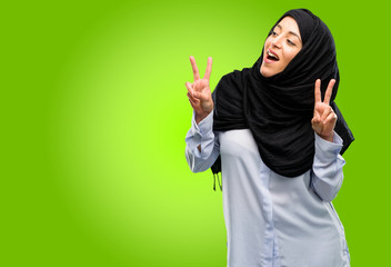 Young arab woman wearing hijab happy and excited expressing winning gesture. Successful and celebrating victory, triumphant