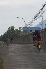 Kampot Cambodia, people on bicycles crossing river via old bridge