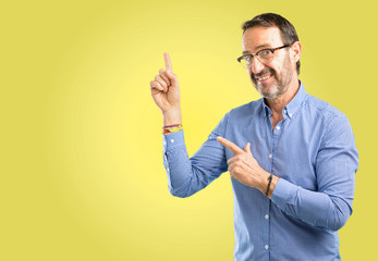 Handsome middle age man pointing away side with his finger