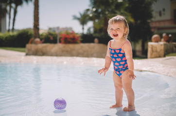 Little cute blonde baby girl infant in swimming pool