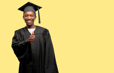 Young african graduate student black man smiling broadly showing thumbs up gesture to camera, expression of like and approval