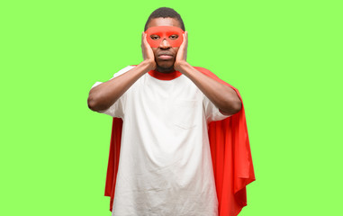 African black super hero man covering ears ignoring annoying loud noise, plugs ears to avoid hearing sound. Noisy music is a problem.