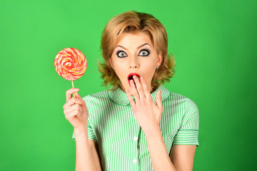 Retro fashion&vintage concept - surprised woman with beauty face with lollipop in pin-up style with retro hairdo. Food sweet&sugar concept - attractive fashion girl with colorful lollipop in hand.