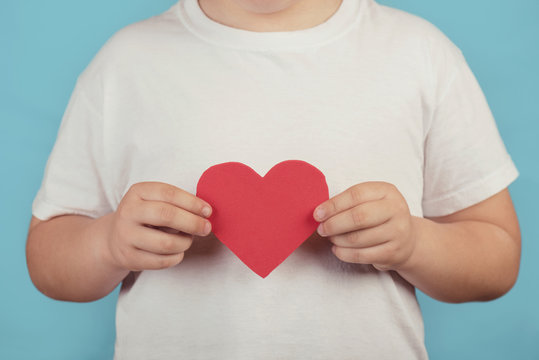 ni&ntilde;o con un coraz&oacute;n sobre fondo azul
