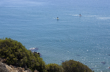 Beautiful view from Rhodes island in the Mediterranean with two unidentified tourists in the distance engaged in stand-up surfing