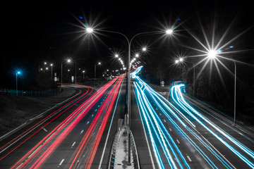 Long exposure selective colour black and white highway with red tail lights and white blue headlights