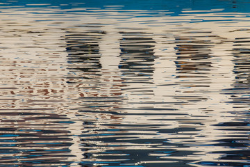 Reflection of windows in the waters of lake created by the light of the setting sun forming...