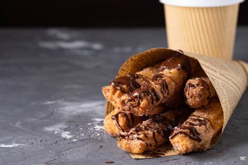 Freshly fried churros (traditional spanish dessert) with hot chocolate and coffee to go in paper bag. Street food concept