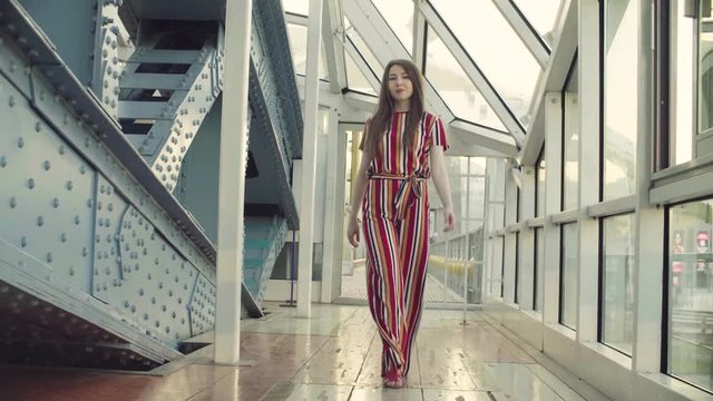 Dolly shot. Attractive woman walking in the modern building and doing dance movements. Inscription on the column - I love Moscow